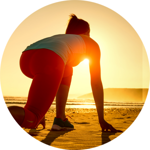 Woman on beach crouched in starting position to run